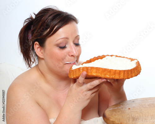 Overweight woman eating sweet cream cake. Obese people enjoying life. Healthy lifestyle theme. 