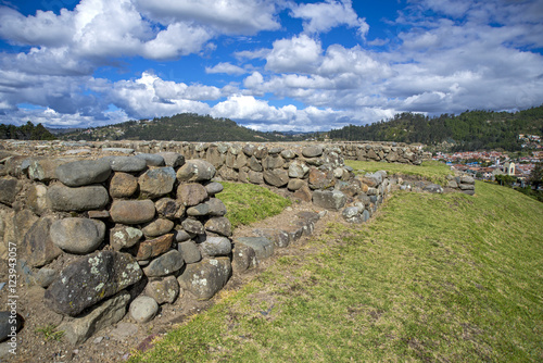 Stone walls of the ancient ruin city of Pumapungo, with the city of Cuenca, Ecuador, in the background, on a sunny morning