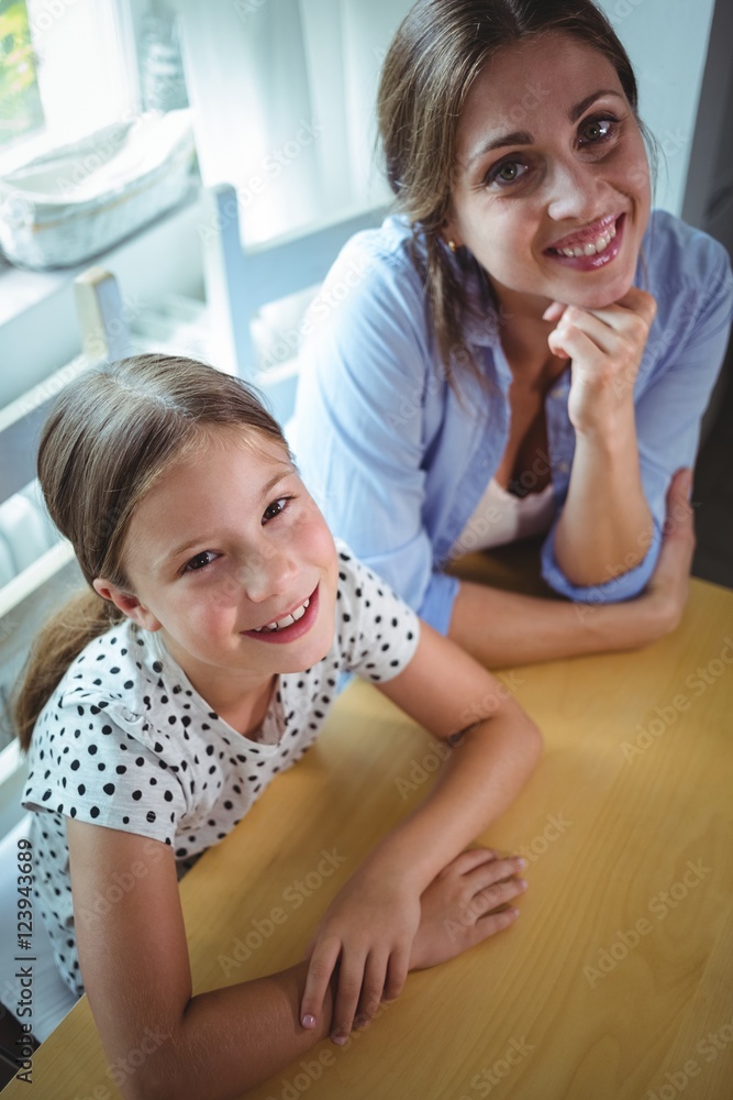 Happy mother and daughter leaning on the table Happy mother and daughter leaning on the table
