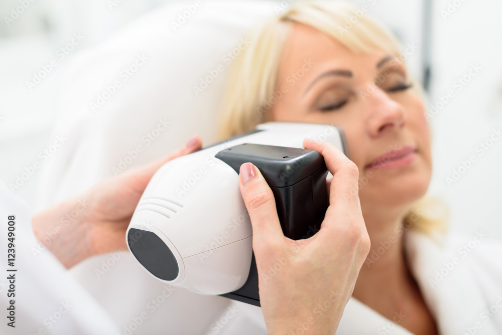 Mature lady enjoying skin rejuvenation by massager Mature lady enjoying skin rejuvenation by massager