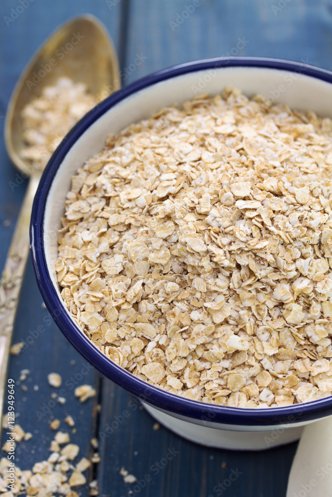oat on white bowl on blue wooden background oat on white bowl on blue wooden background