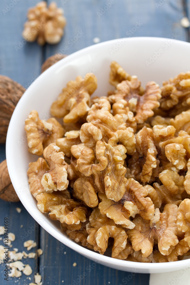 walnut in white bowl on blue wooden background walnut in white bowl on blue wooden background