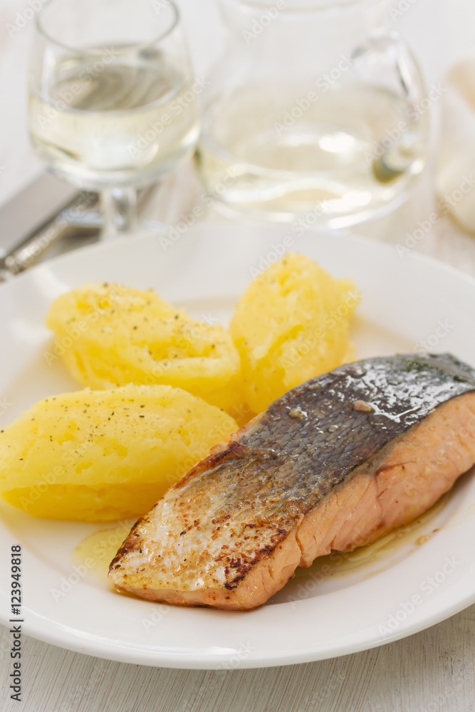 fried salmon with potato on white dish on wooden background