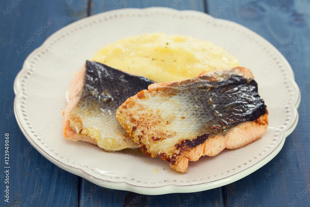 fried salmon with mashed potato on white dish on blue wooden background fried salmon with mashed potato on white dish on blue wooden background