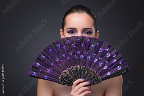 Nice woman with fan against gray background