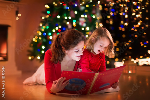 Mother and daughter reading at fire place on Christmas eve