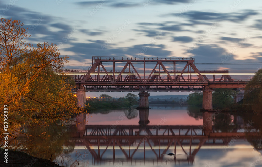 Railway bridge over the river at sunset 