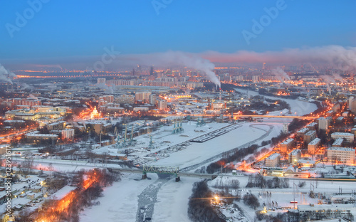 View of dawn on a winter city Moscow. Urban landscape with a frozen river