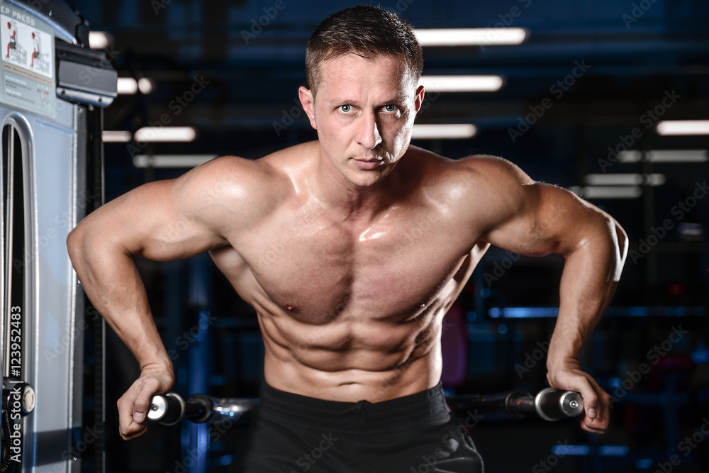 Handsome athletic fitness man posing and trains in the gym. Handsome athletic fitness man posing and trains in the gym.