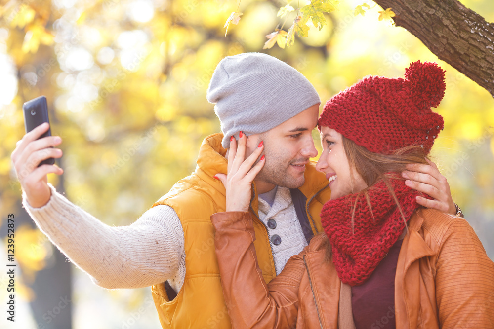 Obraz premium Portrait of young couple in park enjoying together and making selfie.