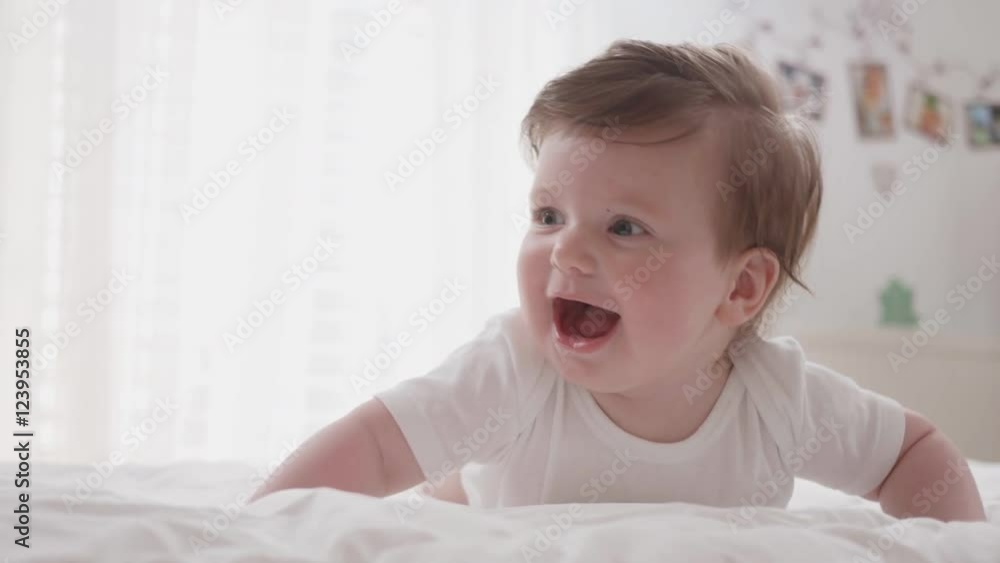 Handheld shot of a cute baby lying on his tummy laughing.
Handheld shot of a cute baby lying on his tummy laughing.