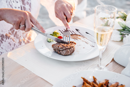 Juicy beef steak, fork and knife with woman's fingers with french manicure
