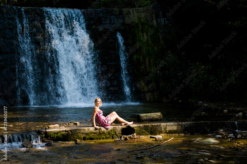 Beautiful young woman by waterfall