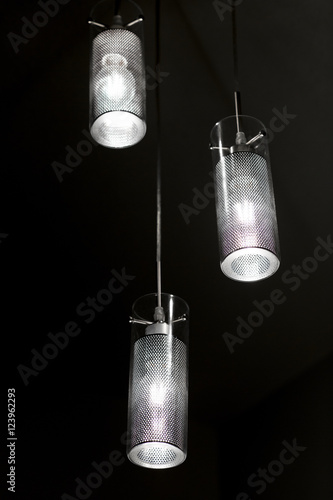 Chandelier made of glass and metal, it is hanging ceiling light. Lamp lights in the dark, room interior. 