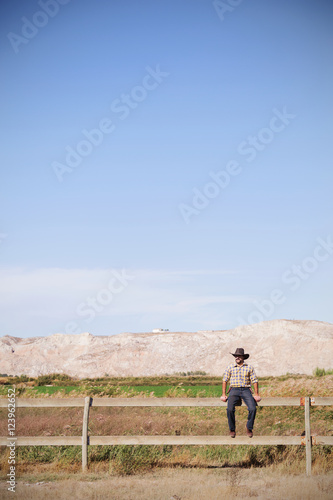 cowboy sitting on a fence