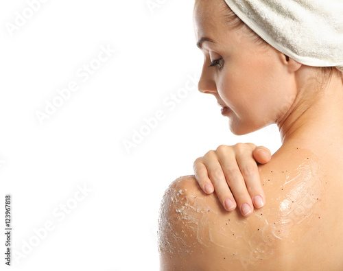 Fototapeta Young woman applying scrub on shoulder on white background
