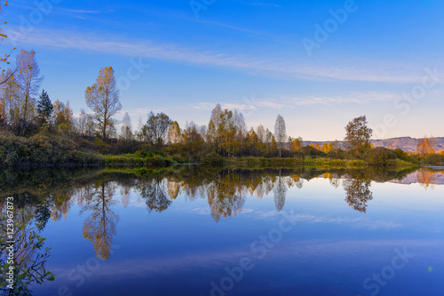 Beautiful fall landscape with blue sky reflected in the water