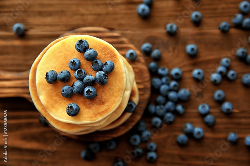 Stack of delicious pancakes with blueberries on wooden cutting board