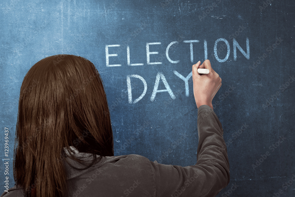 Beauty woman writing a 'ELECTION DAY' on blue chalkboard Beauty woman writing a 'ELECTION DAY' on blue chalkboard