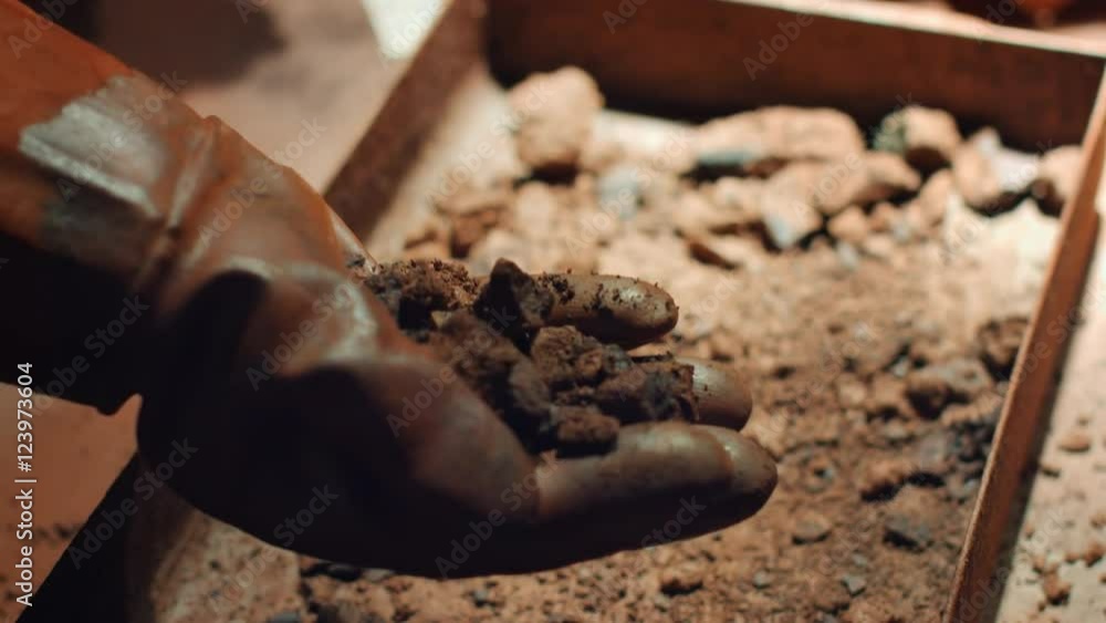 Close up of hand in rough industrial rubber glove take a handful of iron ore Close up of hand in rough industrial rubber glove take a handful of iron ore