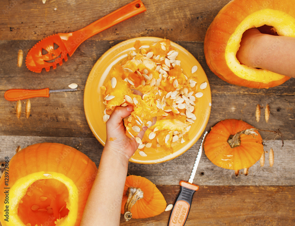 Fototapeta premium Close-up kids hands carving Halloween pumpkins