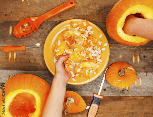 Close-up kids hands carving Halloween pumpkins