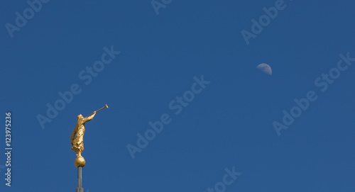 Obraz na plátně Mormon Angel Moroni Statue against a bright blue sky with the Moon