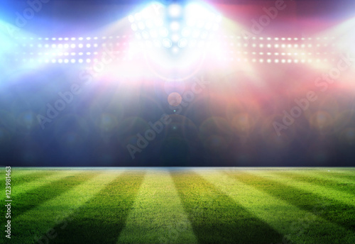 Stadium football game lights are shinning on a green grass field © Kalawin