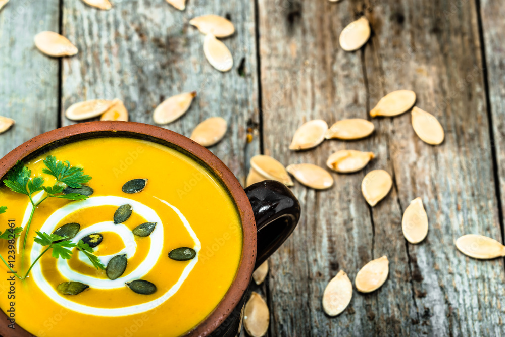 Pumpkin soup with parsley and seeds on wooden table Pumpkin soup with parsley and seeds on wooden table