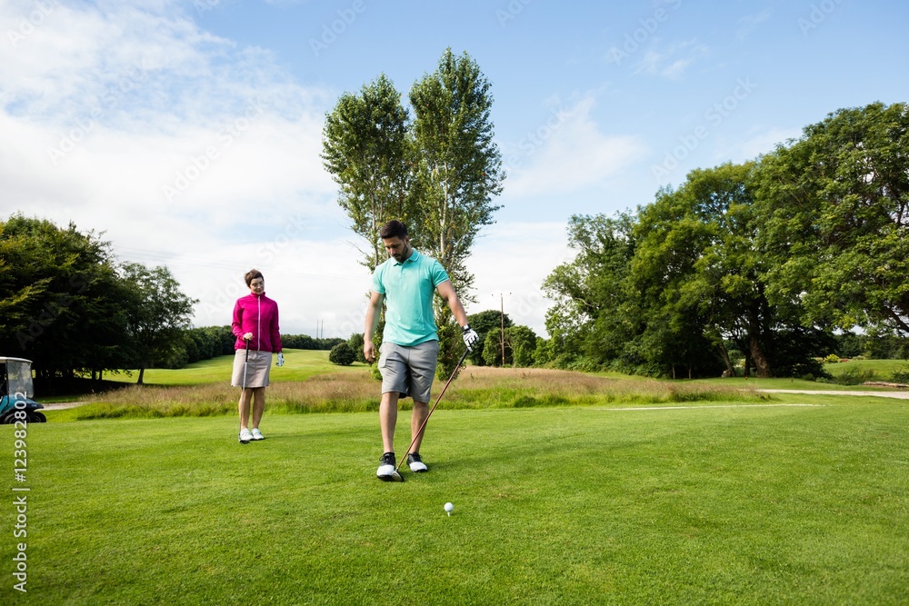 Male instructor assisting woman in learning golf Male instructor assisting woman in learning golf