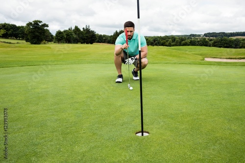 Man squatting to line up his putt