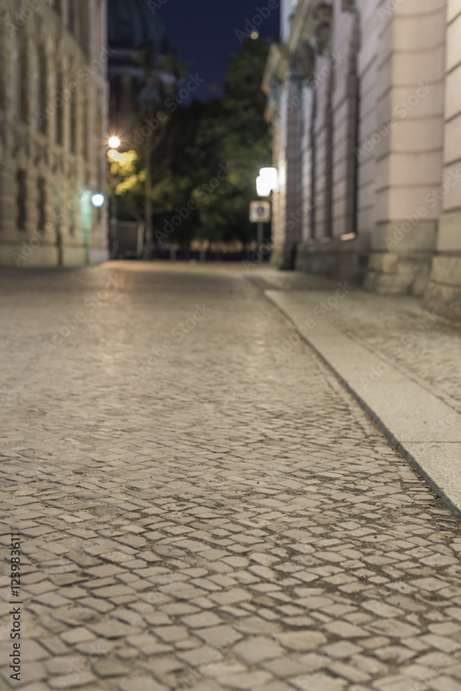empty brick road at night with blurred background, historic midtown of Berlin, Germany, Europe