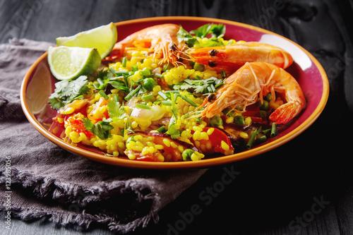 Spanish paella with seafood on the red teralke with lime. Delici