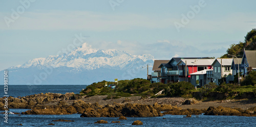Beautiful view of  Queen Charlotte sound snowy mountains from Wellington coast, with houses and the ocean in the foreground © Pikadream