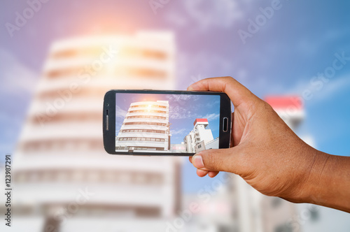 Man hand holding smart phone focused on city landscape 