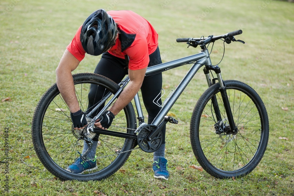 Male mountain biker fixing his bike chain