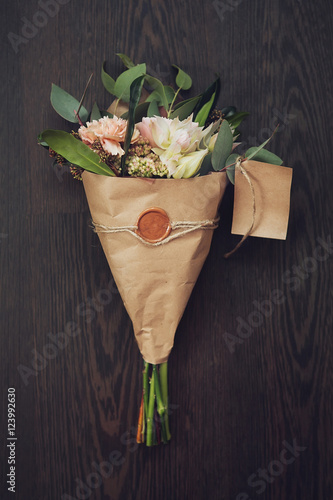 bouquet of flowers in the kraft paper on a dark wooden backgroun