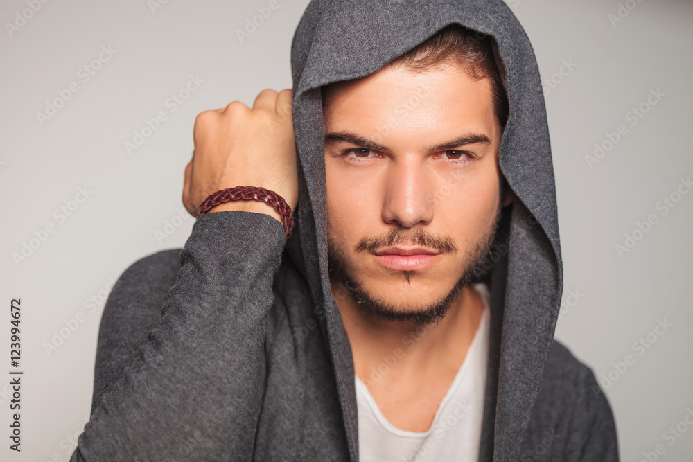 casual man with hoodie on holds hand near head casual man with hoodie on holds hand near head
