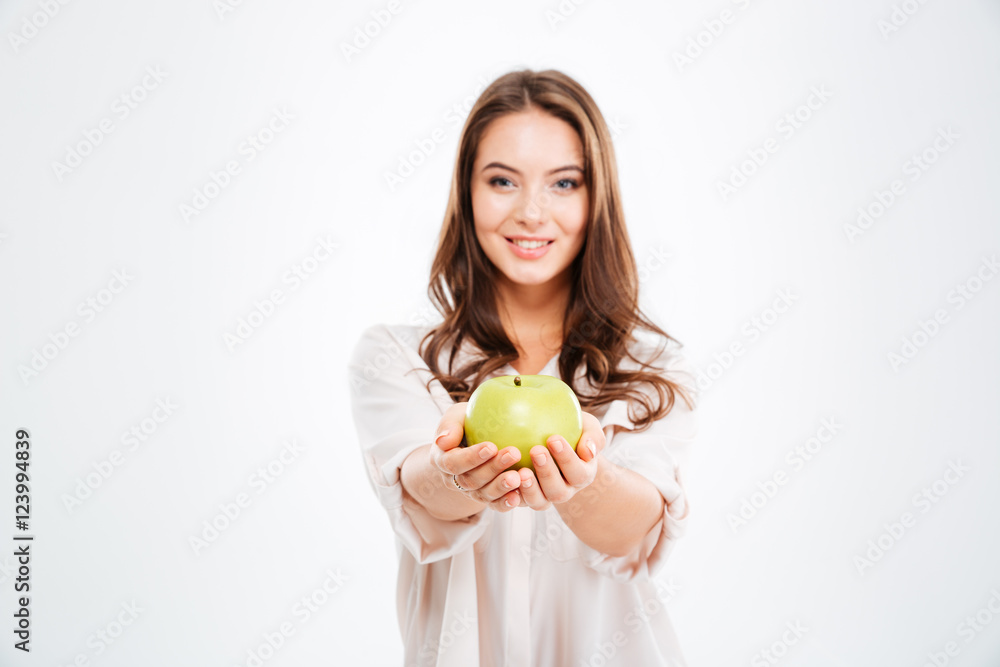 Smiling young woman giving apple at camera Smiling young woman giving apple at camera