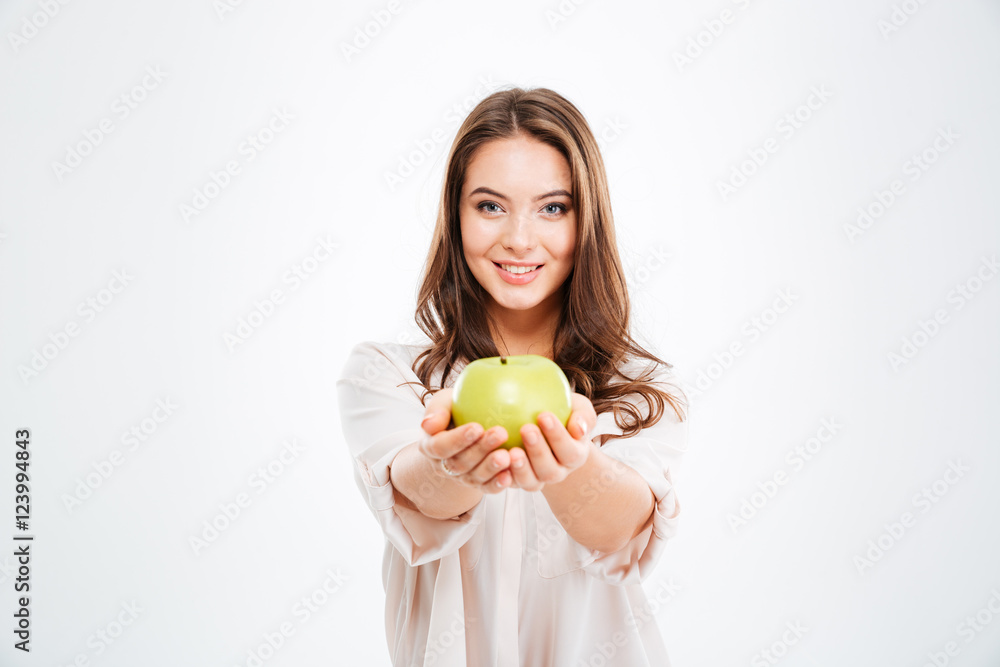 Smiling young woman giving apple at camera Smiling young woman giving apple at camera