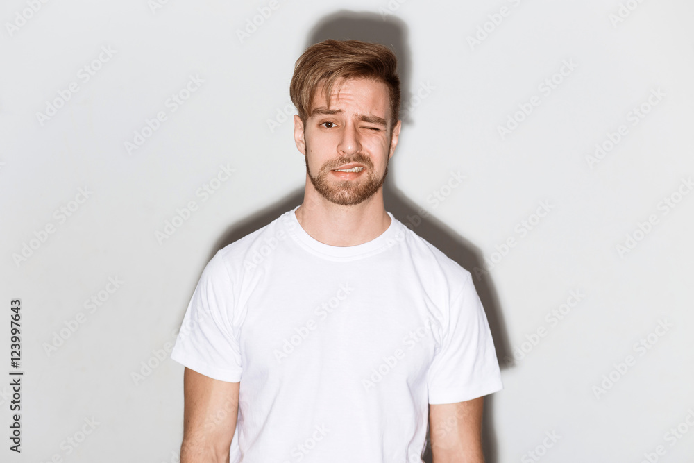 An emotional image of a young caucasian man with a beard in a white t-shirt on a bright background An emotional image of a young caucasian man with a beard in a white t-shirt on a bright background