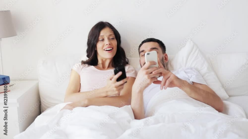 happy couple with smartphones in bed happy couple with smartphones in bed