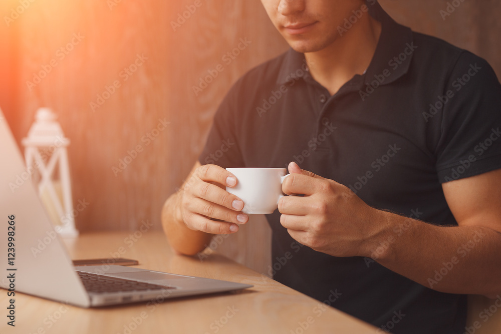 Man drinking a cup of coffee while sitting at wooden table