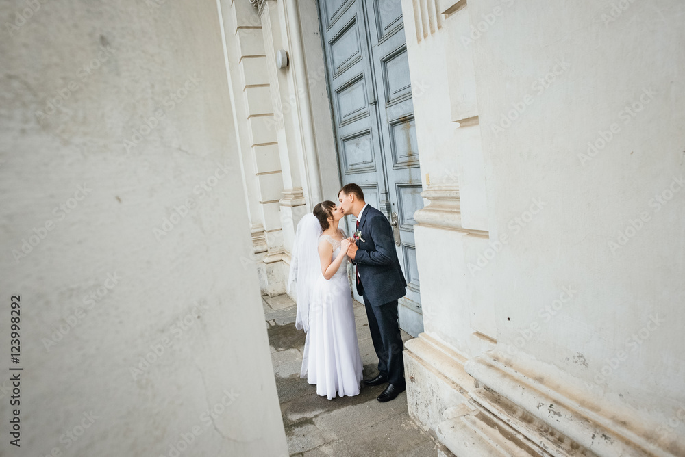 Bride and groom at wedding Day walking Outdoors near architecture. Bridal couple, Newlywed woman and man embracing with love Bride and groom at wedding Day walking Outdoors near architecture. Bridal couple, Newlywed woman and man embracing with love