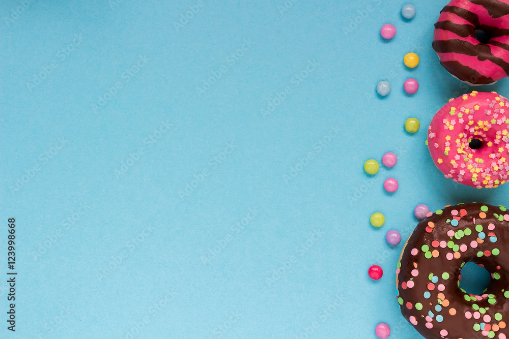 Sweet donuts with colorful candies on the blue background.