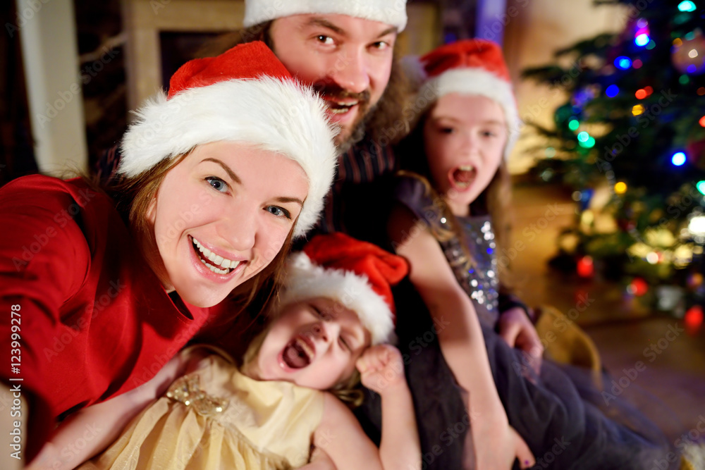 Young happy family of four taking a photo of themselves on Christmas Young happy family of four taking a photo of themselves on Christmas