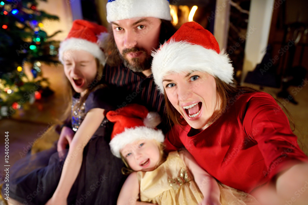 Young happy family of four taking a photo of themselves on Christmas Young happy family of four taking a photo of themselves on Christmas