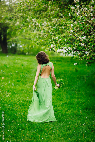 beautiful young woman walking in a green garden