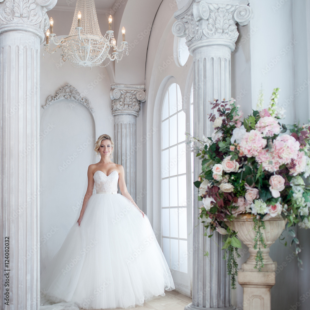 Obraz premium Charming young bride in luxurious wedding dress. Pretty girl, is near big window