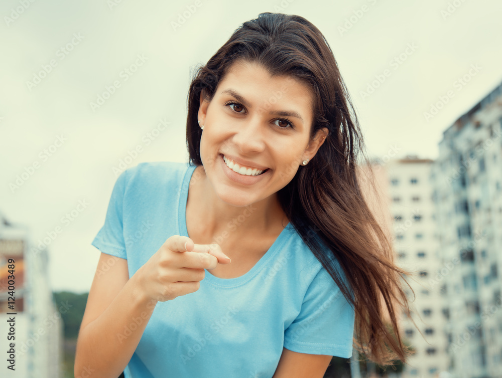 Woman in a blue shirt pointing at camera in cool cinema look